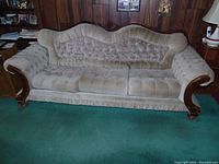 Front view of the French Provincial style couch showing the tufted backrest, floral embroidery on cushions, and carved wooden armrests.