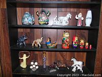 Wooden shelf displaying various knick knacks including nesting dolls, animal figurines, and pottery.