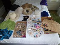 Wide view showing hats, scarves, and jewelry on a table with a mannequin head wearing a purple hat