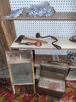 Overview of shelves showing tools including axe, cutting shears, hand drill, scrub board, and Queen Stove Works Superfan heater.