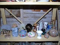Full view of shelf with assortment of small vases and carved stone pieces