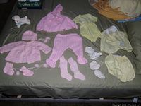 Full layout showing all baby clothing items and lamb planter on a bedspread.