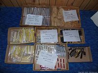 Wide shot of multiple cardboard boxes containing individually packaged watch bands with handwritten count labels