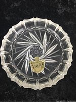 Top view of a single Czech crystal coaster showing intricate starburst and leaf cut design with attached authenticity label