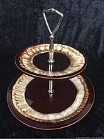Front view of the assembled two-tier dessert tray showing brown and cream mottled plates and silver metal handle.