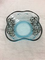 Top view of a blue glass bowl with silver floral overlay along the rim, showing the scalloped edges and detailed silver design.