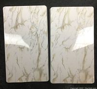 Two small rectangular burner covers with white marble design side by side