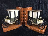Front view of the pair of classic car bookends showing detailed cars with brass fronts and white curtains on wooden bases.