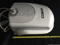 Top view of white Conair main unit with control dial, power cord visible, measuring about 12 inches width and 9 inches height.