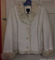 Front view of cream-colored faux suede ladies jacket with faux fur collar, cuffs, and hem. Contains button closures and decorative stitching.