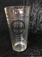 Front view showing Kodak logo on clear thick glass measuring cup with horizontal volume markings.