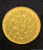 Top view of the vintage large cake plate showing the gold surface with black floral pattern and black rim against a dark background.