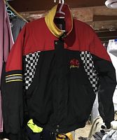 Full front view of the racing jacket showing red upper section, black lower section, checkered side panels, and yellow collar interior.
