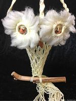 Front view of the owl plant holder showing the yarn macrame craftsmanship with yellow acrylic eyes and real wood perch at the bottom.