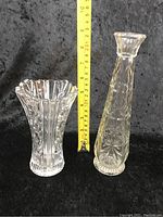 Two vintage glass vases standing upright with a measuring tape showing approximate height.