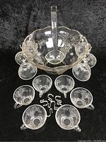 Full view of glass punch bowl set showing punch bowl, ladle, six matching cups with hooks.