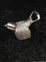 Close-up view of the silver plated bird-shaped bottle opener showing detailed feather texture and metal loop handle.