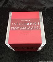 Clear acrylic cube with a red insert that reads 'College TABLE TOPICS Questions to start great conversations' from the front.