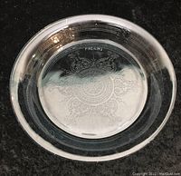 Top-down photo of clear glass pie dish showing etched snowflake design and Fire-King marking in center.
