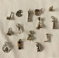 Photo showing 14 vintage sterling silver lucky charms spread on a flat surface