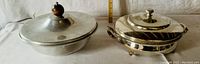 Two vintage silver-plated lidded serving pieces side by side, one footed bowl, one serving platter.