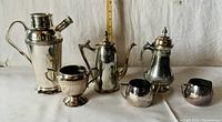 Full set of six vintage silver plated coffee, tea, creamer, and pitcher items on white background with ruler