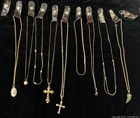 All 9 necklaces with various pendants shown secured individually on black velvet jewelry holder, at full length.