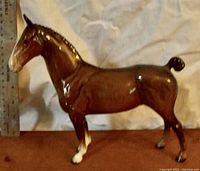 Side profile of the brown porcelain horse figurine showing details, with a ruler beside it measuring height at approx 6 inches