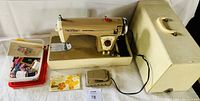 Photo showing entire sewing machine set including machine, foot pedal, cream case, and box of accessories