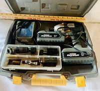 Full view of open plastic carrying case with drill, charger, two batteries and accessory bit tray inside