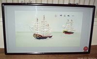 Full view of framed artwork showing two mother of pearl oriental junk boats with Chinese characters on light green background.