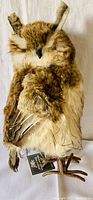 Front view of simulated life-like owl faux fur mantle piece in natural brown and cream tones.