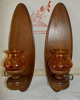 Pair of vintage mid century teakwood wall candle holder sconces with amber glass cups, oval backplates and textured bubble glass.