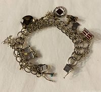 Top view of vintage 1970s sterling silver double link charm bracelet showing multiple charms attached around the bracelet including drum, camera, Christmas tree, and others.