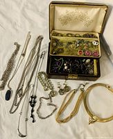 Full view of the jewelry box with various rings, earrings, chains and necklaces laid out.