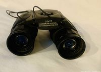 Front top view of black 10x25 waterproof fogproof binoculars showing lenses and markings on top.