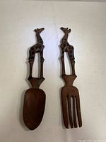 Front view of wooden giraffe salad tongs showing spoon and fork with carved giraffe handles.