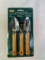 Front view of the packaged houseplant tool set showing three tools with wooden handles and metal parts attached to green backing card.