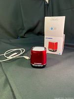 Red mini Hyundai Bluetooth speaker with white USB charging cable and Hyundai branded box in background