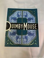 Front cover of 'Quimby the Mouse Collected Works' softcover book, blue with artistic design and title in gold and white.