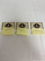 Three gift cards laid flat, front side visible with sticky notes indicating $60, $50, $50 values