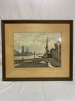 Framed print showing overall artwork of waterfront cityscape with boats and towers.