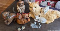 Photo of all six cat-themed items on wooden surface, showing the large yellow cat cookie jar with kittens and wooden cat carvings.