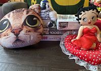 Image showing Betty Boop plush doll, white and black striped musical monkey toy, cat head pillow and stacked boxed puzzles.