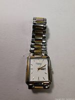 Front view of Caravelle by Bulova watch showing rectangular face with date and two-tone metal band.