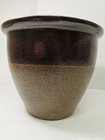 Front view of ceramic planter showing brown glazed upper portion and textured beige lower half.