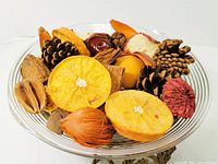 Close-up of the clear glass bowl filled with dried autumn decor such as pine cones, dried citrus slices, and seed pods