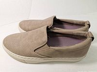 Pair of men's beige leather slip-on shoes with textured upper and white rubber soles.