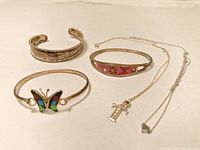 Photo showing two sterling silver necklaces and three bracelets with enamel and engraved details.