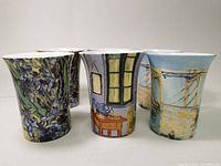 Six porcelain mugs arranged in two rows showing their colorful exterior art designs with a slight flared top shape